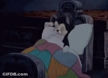 A Cartoon Character Is Laying On A Bed With A Blanket And A Statue . GIF