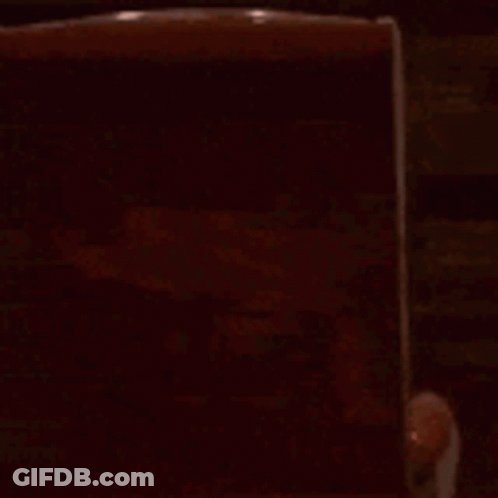 A Cartoon Character Is Sitting In A Chair In A Dark Room Watching A Movie . GIF
