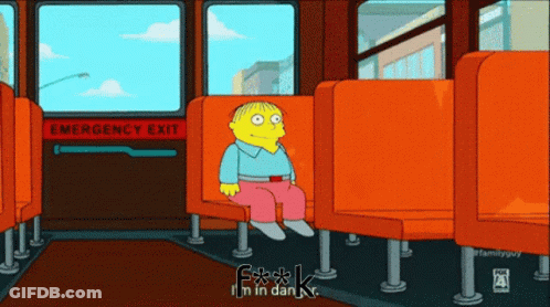 A Cartoon Character Is Sitting In An Orange Seat In Front Of An Emergency Exit Sign GIF