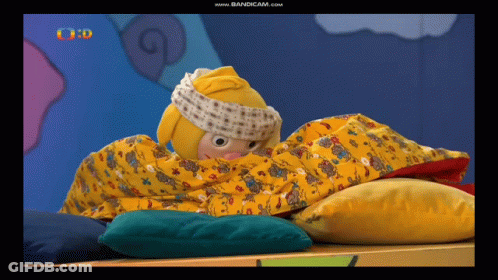 A Cartoon Character Is Wrapped In A Yellow Blanket On A Bed GIF