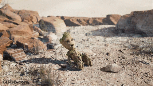 A Cartoon Character Named Groot Is Sitting On The Ground In The Desert GIF