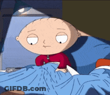 A Cartoon Character Sitting In A Bed With A Blue Blanket GIF