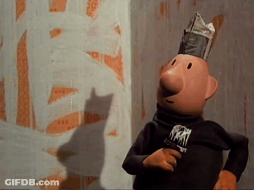 A Cartoon Character Wearing A Newspaper Hat Is Standing In Front Of A Wall With A Shadow Of A Cat On It GIF
