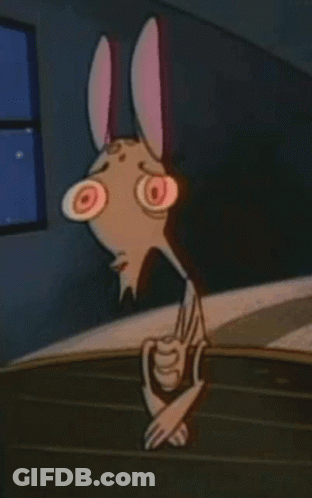 A Cartoon Character With Bunny Ears And Big Red Eyes Is Standing Next To A Table . GIF