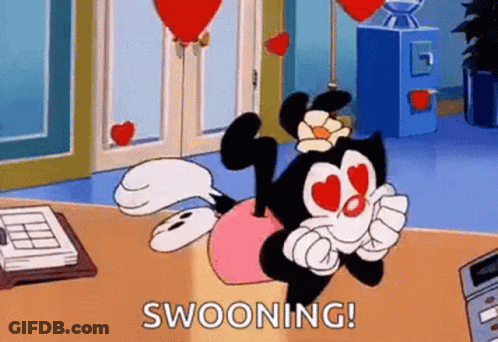A Cartoon Character With Hearts In Her Eyes Is Sitting On A Desk With Balloons In The Background . GIF