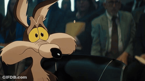 A Cartoon Coyote With Big Yellow Eyes Looks At The Camera GIF