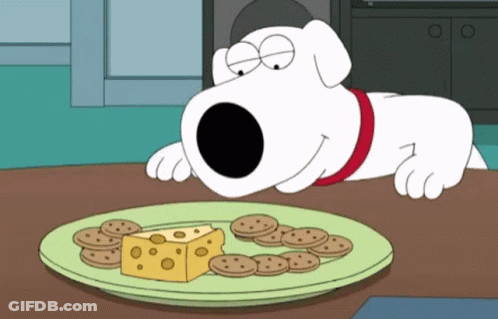 A Cartoon Dog Laying On A Table Looking At A Plate Of Cheese And Cookies GIF