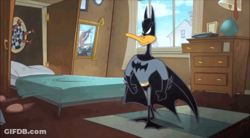 A Cartoon Duck Dressed As Batman Is Standing In A Bedroom GIF