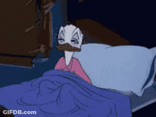 A Cartoon Duck Is Laying In Bed With A Blue Blanket GIF