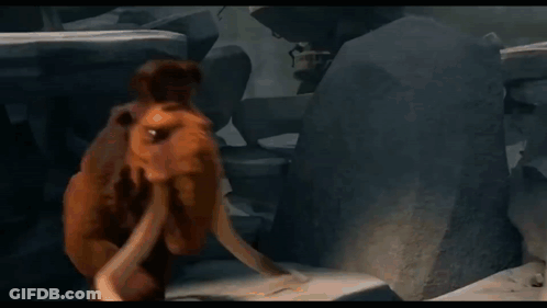 A Cartoon Elephant With Long Tusks Is Standing In Front Of A Rock Wall . GIF