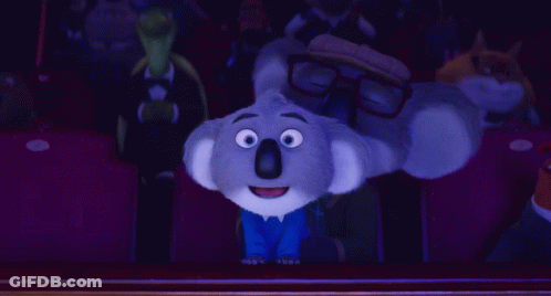 A Cartoon Koala Wearing Glasses Is Sitting In A Theater GIF