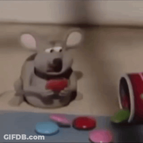 A Cartoon Mouse Is Sitting On A Table Eating A Heart Shaped Candy . GIF