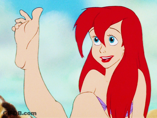A Cartoon Of A Girl With Red Hair And Blue Eyes Holding Her Foot Up GIF