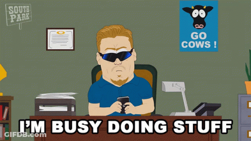 A Cartoon Of A Man Sitting At A Desk With The Words I 'M Busy Doing Stuff Above Him GIF