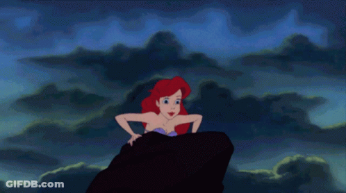A Cartoon Of A Mermaid Sitting On A Rock In The Ocean GIF