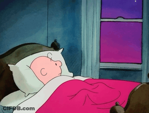 A Cartoon Of Charlie Brown Sleeping In A Bed GIF