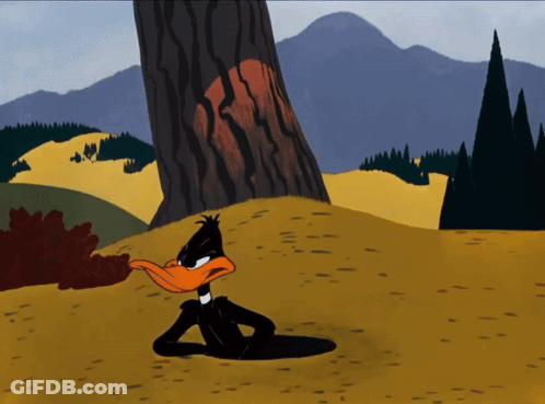A Cartoon Of Daffy Duck Laying In The Dirt Near A Tree GIF