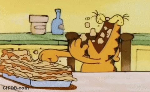 A Cartoon Of Garfield Eating A Lasagna On A Table . GIF