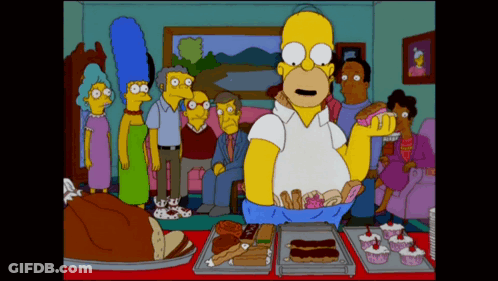 A Cartoon Of Homer Simpson Standing In Front Of A Table Full Of Desserts GIF
