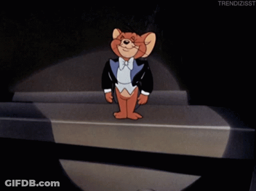 A Cartoon Of Jerry In A Tuxedo Stands On A Stage With A Microphone GIF