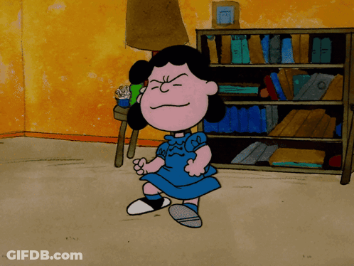 A Cartoon Of Lucy Brown Standing In Front Of A Bookcase GIF