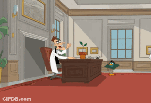 A Cartoon Of Perry The Platypus Sitting At A Desk With A Plant GIF