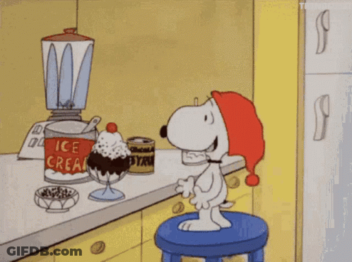 A Cartoon Of Snoopy Sitting On A Stool In Front Of An Ice Cream Sundae In A Kitchen GIF