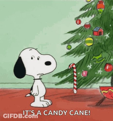 A Cartoon Of Snoopy Standing Next To A Christmas Tree With A Candy Cane GIF