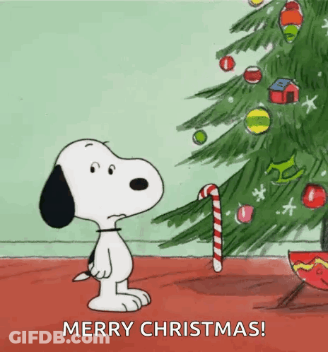 A Cartoon Of Snoopy Standing Next To A Christmas Tree With A Candy Cane GIF