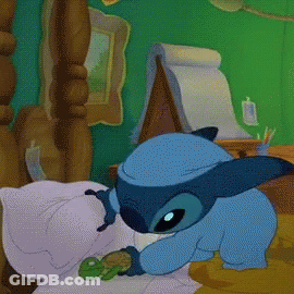 A Cartoon Of Stitch Laying On A Bed GIF