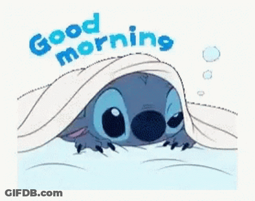 A Cartoon Of Stitch Laying Under A Blanket With The Words `` Good Morning '' Written Above Him . GIF
