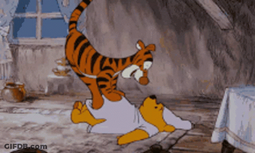 A Cartoon Of Winnie The Pooh Laying On The Floor With A Tiger On Top Of Him GIF