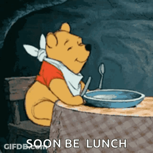 A Cartoon Of Winnie The Pooh Sitting At A Table With A Bowl Of Food And The Words Soon Be Lunch GIF