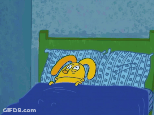 A Cartoon Rabbit Is Laying In A Bed With A Blue Blanket GIF