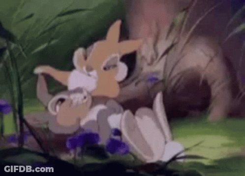 A Cartoon Rabbit Is Laying On The Ground In The Grass . GIF