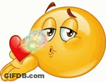 A Cartoon Smiley Face Is Blowing A Kiss While Holding A Red Heart . GIF