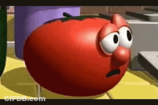 A Cartoon Tomato With Big Eyes And A Big Nose Is Sitting On A Table . GIF