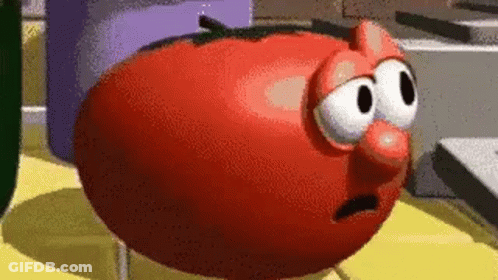 A Cartoon Tomato With Big Eyes And A Red Nose Is Standing On A Table . GIF