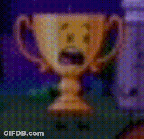 A Cartoon Trophy With A Surprised Face On It Is Standing Next To A Wii Controller . GIF