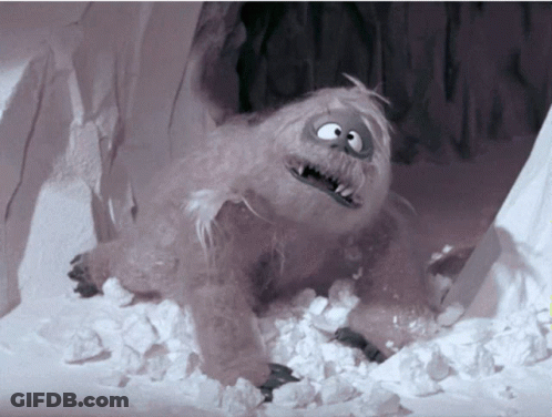 A Cartoon Yeti Is Laying In The Snow And Looking At The Camera GIF