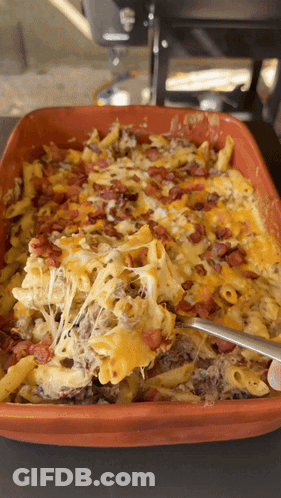 A Casserole Dish Filled With Macaroni Cheese Bacon And A Spoon GIF