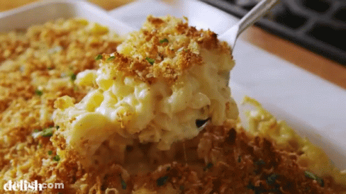 A Casserole Dish With Macaroni And Cheese And A Spoon In It GIF