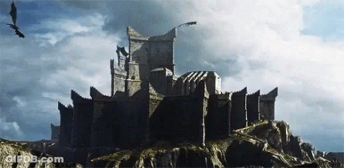 A Castle On Top Of A Rocky Hill With Dragons Flying Around It GIF