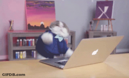 A Cat Is Using An Apple Laptop On A Table GIF
