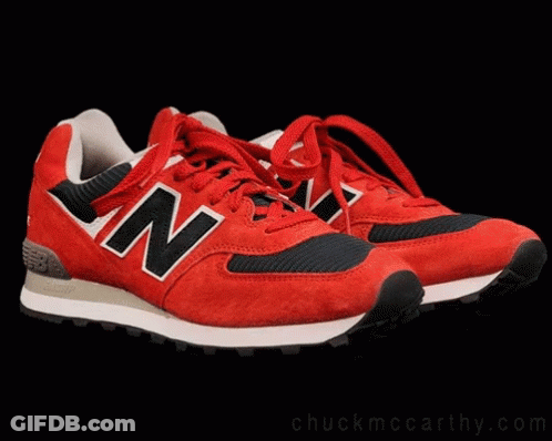 A Cat Sitting On Top Of A Pair Of Red New Balance Shoes GIF