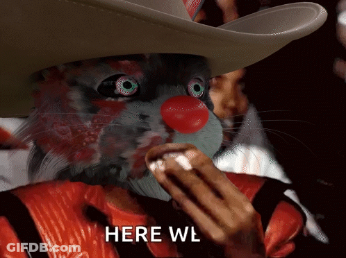 A Cat Wearing A Cowboy Hat And A Red Nose Eating A Hot Dog With The Words Here Wl Below It GIF