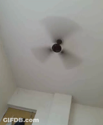 A Ceiling Fan Is Spinning In A Room . GIF