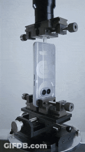 A Cell Phone Is Being Tested On A Machine With A Microscope In The Background GIF