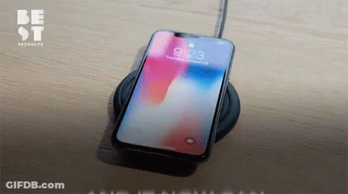 A Cell Phone Sitting On A Charger With The Time 9:23 On The Screen GIF