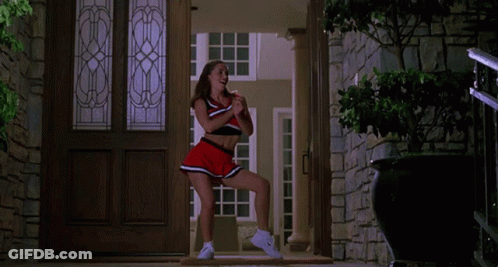 A Cheerleader In A Red And Black Outfit Is Dancing In A Doorway GIF
